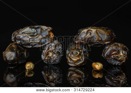 Group Of Six Whole One Piece Of Dried Brown Date Medjool Isolated On Black Glass