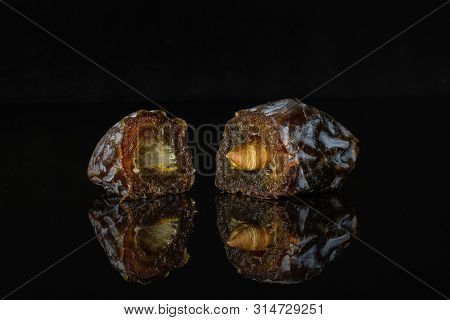 Group Of Two Halves Of Dried Brown Date Medjool Isolated On Black Glass