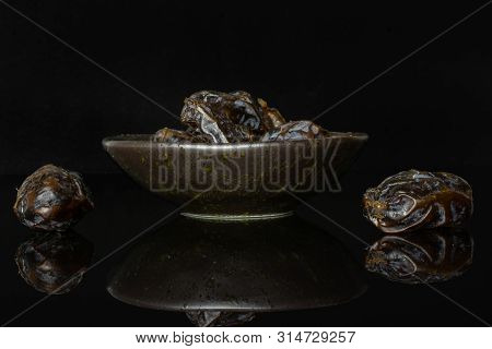 Lot Of Whole Dried Brown Date Medjool On Grey Ceramic Plate Isolated On Black Glass