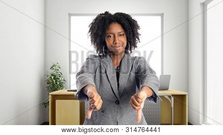 Black African American Businesswoman In An Office With Thumbs Down.  She Is An Owner Or An Executive