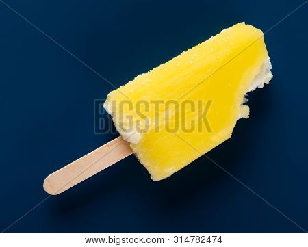 Yellow Popsicle With Some Bites On A Dark Blue Background