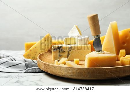 Different Types Of Delicious Cheese In Plate On Marble Table Against Light Background
