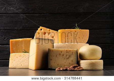 Different Types Of Delicious Cheese On Table Against Wooden Background