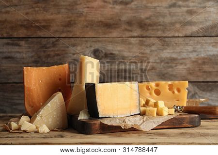 Different Types Of Delicious Cheese On Table Against Wooden Background