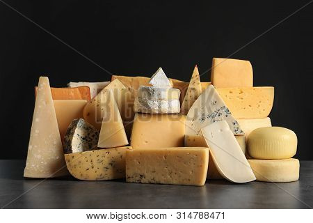 Different Types Of Delicious Cheese On Table Against Black Background