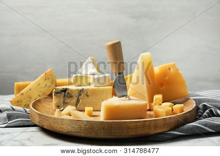 Wooden Plate With Different Types Of Delicious Cheese On Marble Table Against Light Background