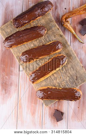 Tasty And Beautiful Eclairs With Chocolate On A Wooden Board. Appetizing Dessert. Party Supplies