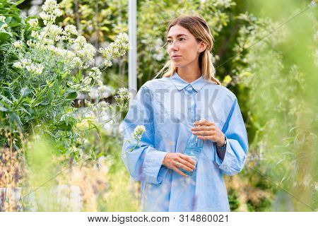 Young And Attractive Woman Drinking Sparkling Water From Glass Eco Biodegradable Bottle At Modern Pa