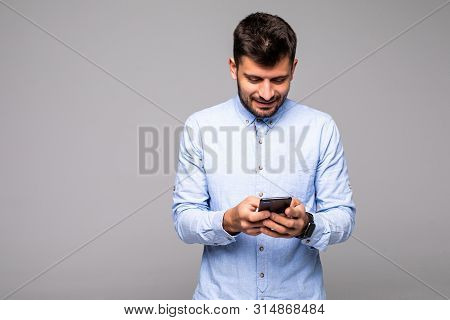 Happy Man In Glasses Typing Sms On Gray Background