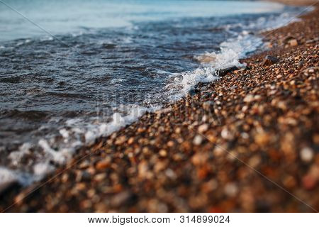 Sea Waves Of The Blue Sea With Foam Roll Ashore The Golden Shore. Close-up