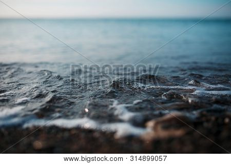 Sea Waves Of The Blue Sea With Foam Roll Ashore The Golden Shore. Close-up