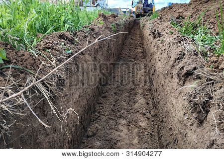 Construction Excavator Digging A Shallow Groove For Electrical Wiring Or Cable.