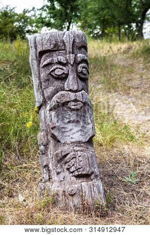 Wooden Idol Of Slavic God By A Path In The Forest. Forest In The Background.