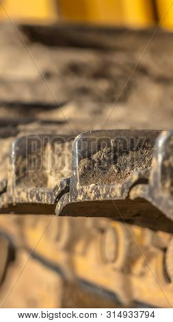 Vertical Close Up Of The Metal Grouser Pad Of A Yellow Contruction Machine On A Sunny Day