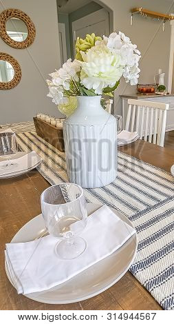 Vertical Table Setting Inside A Dining Room With Brown Table And White Chairs