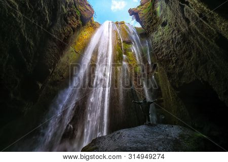 Traveler Stunned By Gljufrabui Waterfall Cascade In Iceland. Location: Gljufrabui Waterfall, Part Of