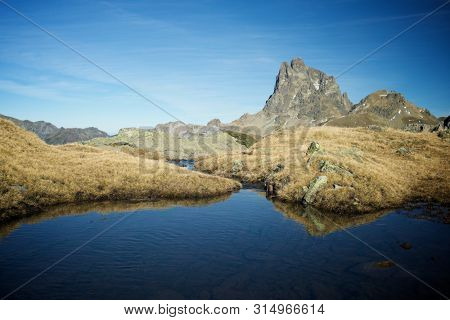 Midi Dossau Peak reflected in a lake. Ossau Valley, Pyrenees National Park, Pyrenees, France.