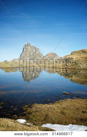 Midi Dossau Peak reflected in a lake. Ossau Valley, Pyrenees National Park, Pyrenees, France.