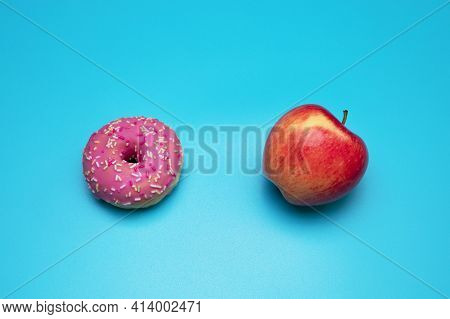 Donut And Apple On The Blue Background. Choosing Between Apple And Donut.