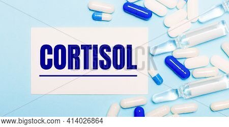 Pills, Ampoules And A White Card With The Text Cortisol On A Light Blue Background. Medical Concept