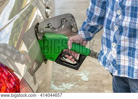 Horizontal Shot Of A Woman From The Right Below Shoulders Down Pumping Gas Into Her Car.