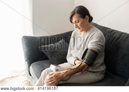 Senior Woman Checking Blood Pressure Level At Home, Older Female Suffering From High Blood Pressure 