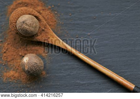 Nutmeg .whole And Ground Nutmeg In A Wooden Spoon Close-up On A Schiffer Background. And Herbs Conce