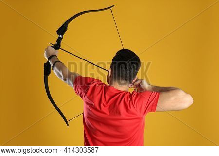 Man With Bow And Arrow Practicing Archery On Yellow Background, Back View