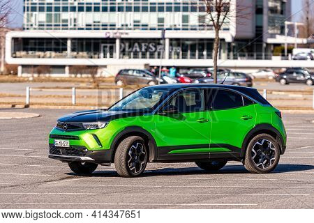 Riga, Latvia - 26 March, 2021: Green Electric Vehicle Opel Mokka-e In The Parking Lot On The Backgro