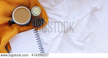 Sweater And Cup Of Coffee With Notebook, Candles, Cone And Knitting Yeallow Clothes On A White Crump