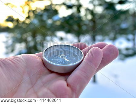 Compass In Hand On Snow Background. Orientation On Terrain In Forest And Mountain In Winter Time. Ma