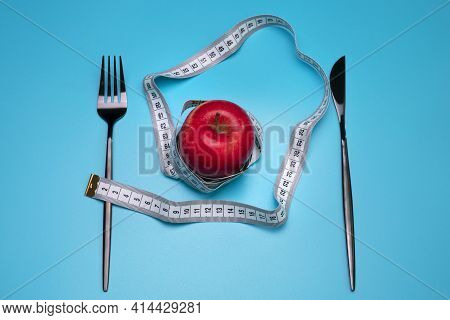 Tomato And Measuring Tape On The Blue Background. The Concept Of Diet.