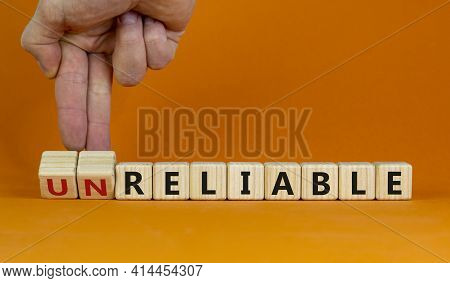 Unreliable Or Reliable Symbol. Businessman Turns Wooden Cubes And Changes The Word Unreliable To Rel
