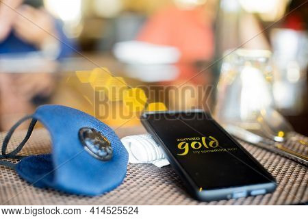 Blue Cloth Mask With Mobile Phone At Side With A Zomato Gold Logo In Restaurant Showing The Populari