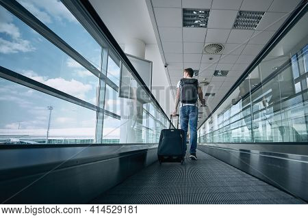 Man Walking With Suitcase. Rear View Of Traveler On Moving Walkway At Airport Terminal.