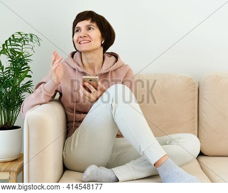 Mature Woman Recording Audio Message, Speaking To Microphone Of Mobile Phone, Smiling And Gesturing.