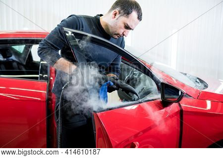 Car Service Worker Cleans Interiror With Steam Cleaner