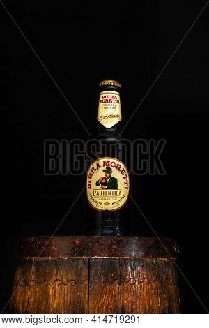 Bottle Of Birra Moretti Beer On Wooden Barrel With Dark Background. Illustrative Editorial Photo Buc