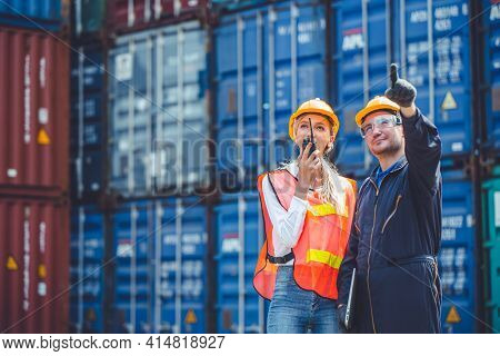 Logistic Worker Man And Woman Working Team With Radio Control Loading Containers At Port Cargo To Tr