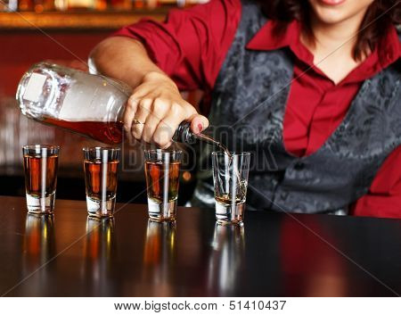 Beautiful redhead barmaid making shots