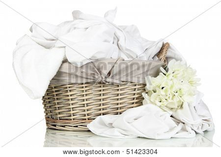 Rumpled bedding sheets in wicker basket isolated on white