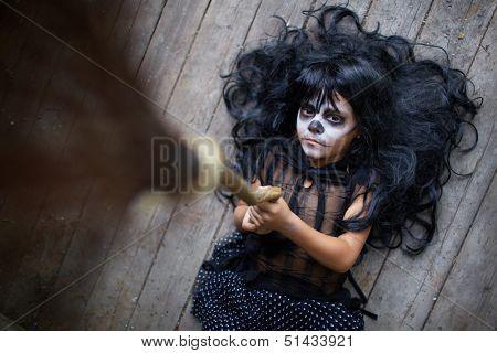 Portrait of eerie girl with broom and looking at camera