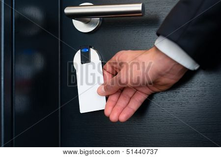 Hotel door - Young man holding a keycard in front of the electronic sensor of a room door 