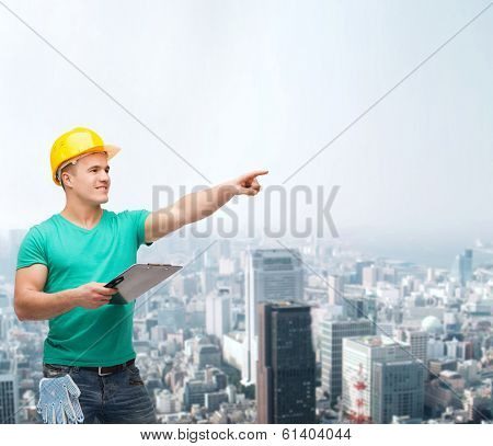 repair, construction and maintenance concept - smiling man in helmet with clipboard pointing finger