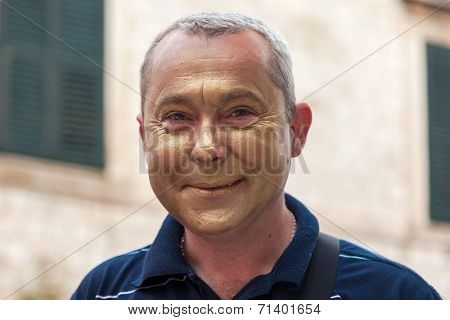 DUBROVNIK, CROATIA - MAY 27, 2014: Local street performer on Stradun putting golden makeup before his performance. Stradun is 300 meters long main pedestrian street in Dubrovnik.