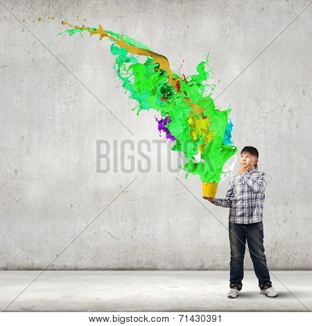 Young boy splashing colorful paint from bucket