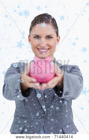 Smiling bank clerk offering piggy bank against snow falling