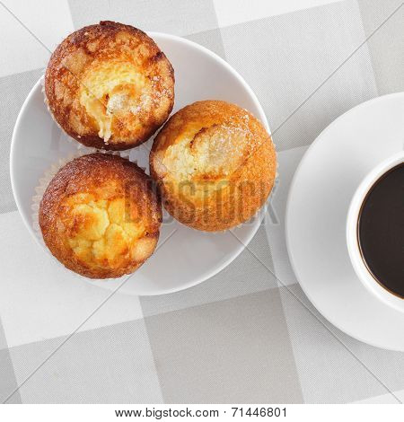 a plate with some magdalenas, typical spanish plain muffins, and a cup of coffee on a set table