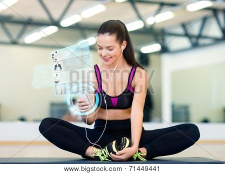 fitness, sport, training, technology and lifestyle concept - smiling young woman with smartphone and earphones in gym