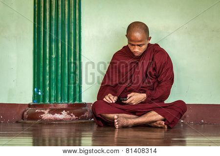 YANGON, MYANMAR - JANUARY 3, 2014: Buddhist monk with phone in Shwedagon Paya pagoda. Yangon, Myanmar